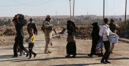 Soldados iraquianos evacuam civis durante os confrontos com membros do Estado Islâmico a sudoeste de Mossul.
