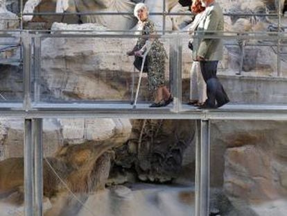 Três visitantes passeiam pela passarela sobre a Fontana de Trevi.