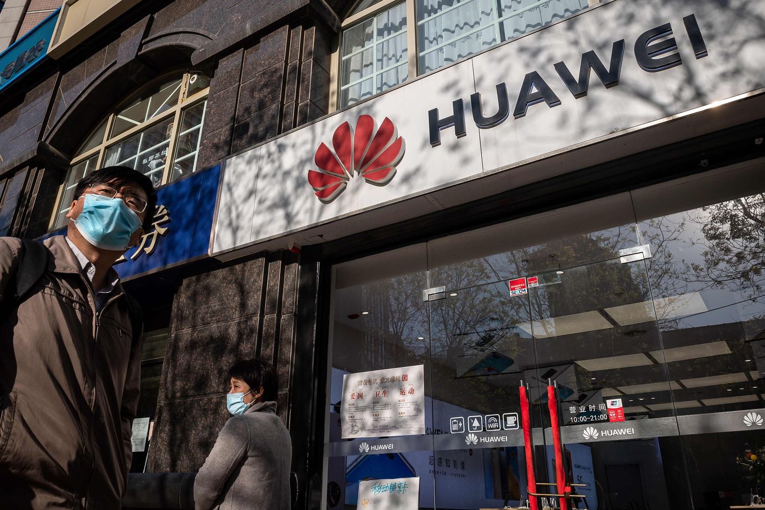 Nesta foto de arquivo, tirada em 22 de abril, pessoas passam diante de uma loja da Huawei em Pequim.