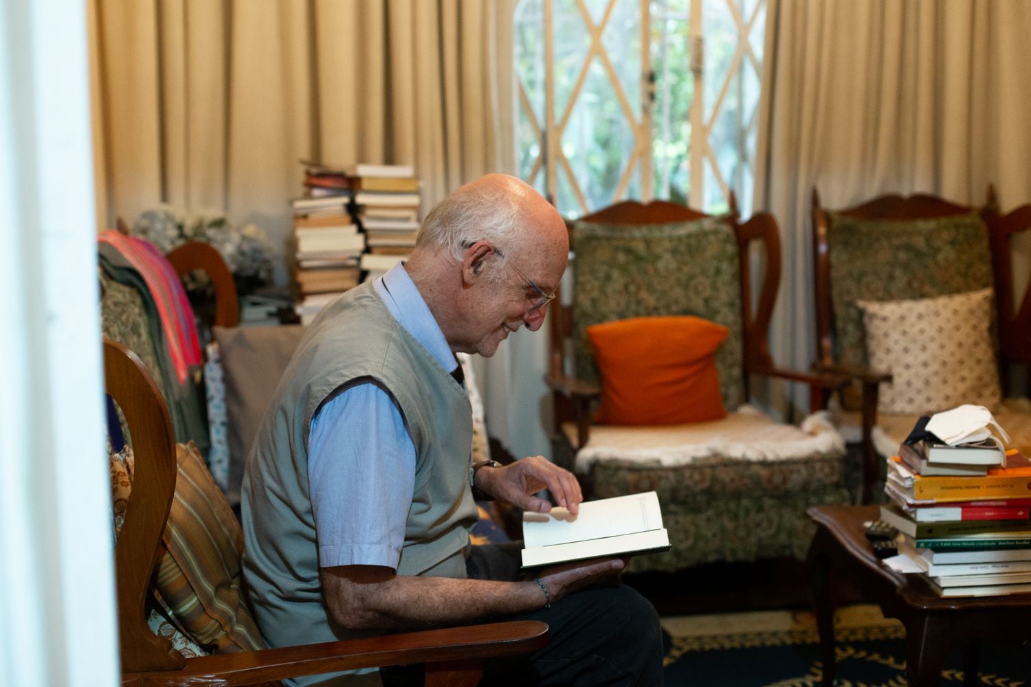 O padre Julio Lancellotti manuseia um livro na sala de sua casa, em São Paulo.