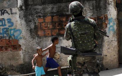 Crianças observam patrulhas das forças armadas durante uma operação contra traficantes no complexo de favelas de Lins, no Rio de Janeiro.