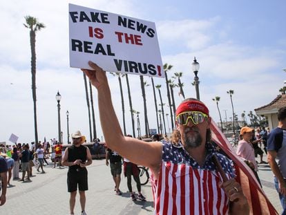 Manifestante na Califórnia levanta cartaz que diz "Fake news são os vírus de verdade", em maio.