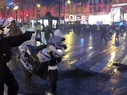 Policial tenta dispersar manifestantes na avenida Champs Elysées, em Paris