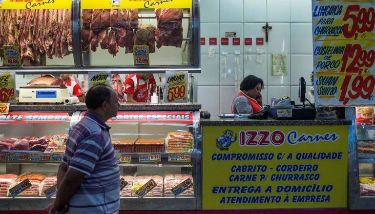 Homem olha carnes em mostrador em São Paulo.