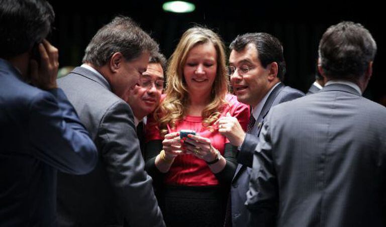 Senadores olham telefone celular no plenário.
