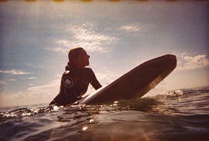 A surfista na água, onde passa grande parte do seu dia.