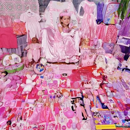 Menina mostra seus brinquedos cor-de-rosa.