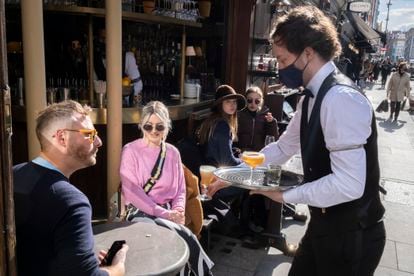 Um garçom atende clientes em um bar de Londres, em 12 de abril.