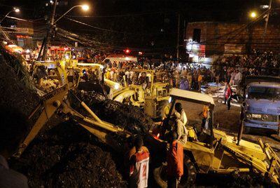 Duas retroescavadeiras retiram os escombros em uma favela de Niterói.