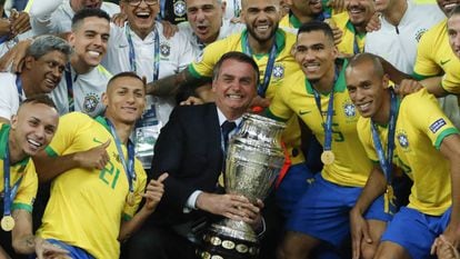 Bolsonaro posa com a taça ao lado dos jogadores da seleção.