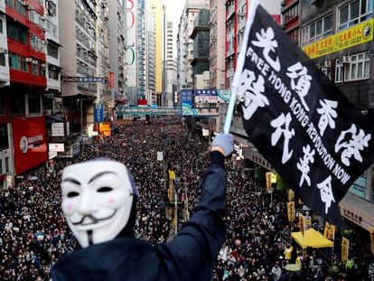 Manifestante mascarado ergue faixa em Hong Kong, neste domingo.