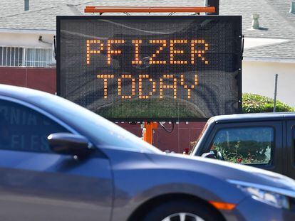 Automóveis passam diante uma placa informativa anunciando a vacina da Pfizer em um centro de imunização de Los Angeles (Califórnia).