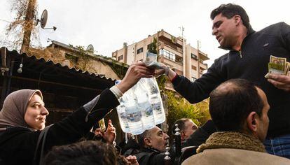 Um homem vende garrafas de água mineral num bairro de Damasco.