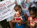 Children holding dolls covered with fake blood stand next to a sign that reads in Portuguese "Stop killing our children. We love you" during a protest against the killing of Emily Victoria Silva dos Santos, 4, and Rebeca Beatriz Rodrigues dos Santos, 7, in Duque de Caxias, Rio de Janeiro state, Brazil, Sunday, Dec. 6, 2020. The girls were killed by stray bullets while playing outside their homes. (AP Photo/Bruna Prado)