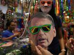 A woman places a mask depicting  Brazil's former President Luiz Inacio Lula da Silva (up) while a shopper holds a mask of Brazil’s President Jair Bolsonaro (down) inside a shop ahead of Carnival festivities in Sao Paulo, Brazil, February 14, 2020. REUTERS/Rahel Patrasso
