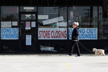 Mulher passa diante de vitrine de uma loja fechada, na quarta-feira, em Niles (Illinois).