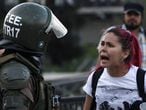 Una manifestante discute con un carabinero en las protestas de Santiago de Chile.