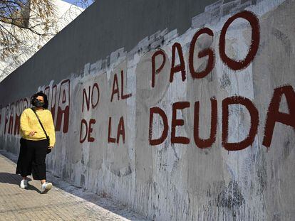 Uma mulher passa em frente a uma pichação contra o pagamento da dívida, em Buenos Aires.