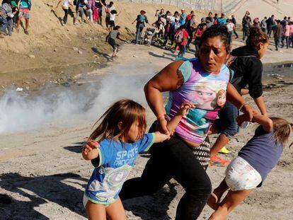 Família foge das bombas de gás lacrimogêneo próximo à fronteira entre os EUA e o México neste domingo, 25