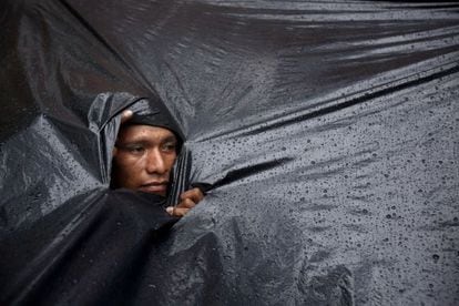 Um indígena mbyá guarani se protege da chuva.