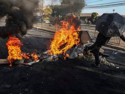 Manifestante chuta os destroços de uma barricada em chamas durante um protesto no bairro de Cerrillos, em Santiago, na sexta-feira, 22 de maio.