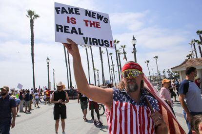 Manifestante na Califórnia levanta cartaz que diz "Fake news são os vírus de verdade", em maio.
