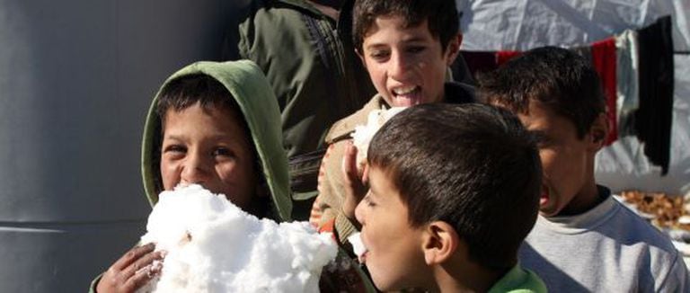 Crianças brincam com neve em um campo de refugiados no Líbano.