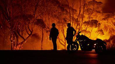 LAKE TABOURIE, AUSTRALIA - JANUARY 04: Residents look on as flames burn through bush on January 04, 2020 in Lake Tabourie, Australia. A state of emergency has been declared across NSW with dangerous fire conditions forecast for Saturday, as more than 140 bushfires continue to burn. There have been eight confirmed deaths in NSW since Monday 30 December. 1365 homes have been lost, while 3.6 million hectares have been burnt this fire season. (Photo by Brett Hemmings/Getty Images)