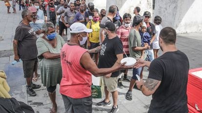 Voluntários entregam marmitas para pessoas em situação de rua, no Rio de Janeiro.