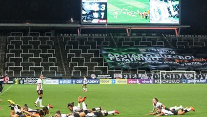 Jogadoras do Corinthians comemoram título brasileiro em 2020. Ao fundo, faixa de apoio ao futebol feminino