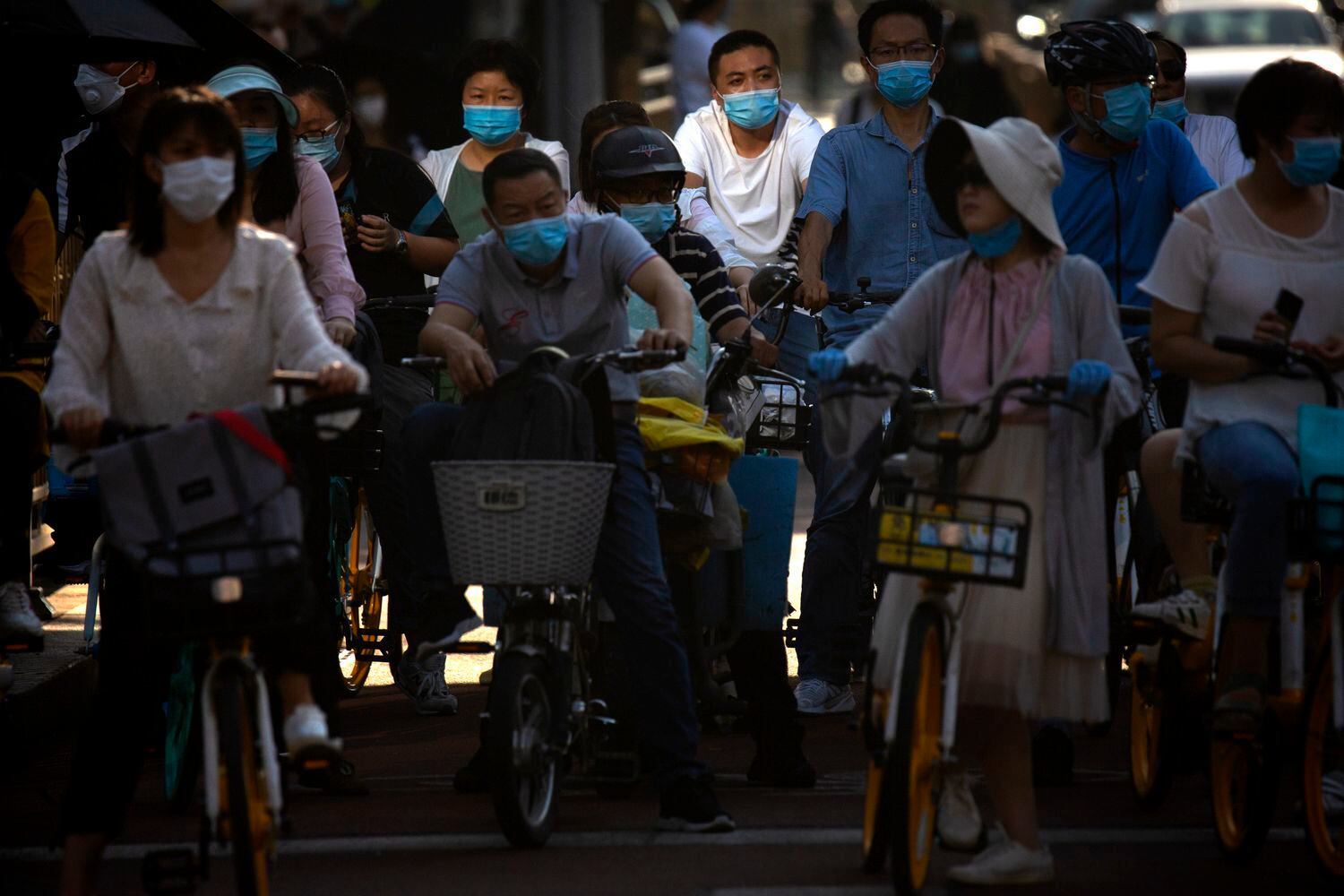 Pessoas usando máscaras de proteção em uma avenida movimentada no centro de Pequim, na China, nesta quarta-feira. País começa a liberar entrada de estrangeiros após surto de covid-19.