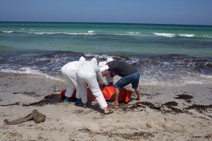 Trabalhadores transladam cadáver de imigrante afogado em frente à costa líbia.
