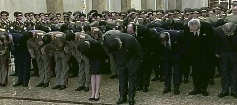 Kim Jong-un (no centro) inclina-se diante da estátua de seu pai.