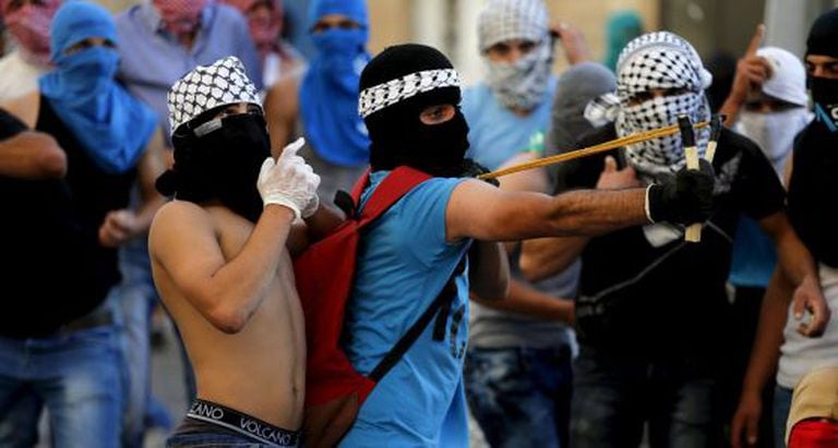 Palestino joga pedras contra a polícia israelense.