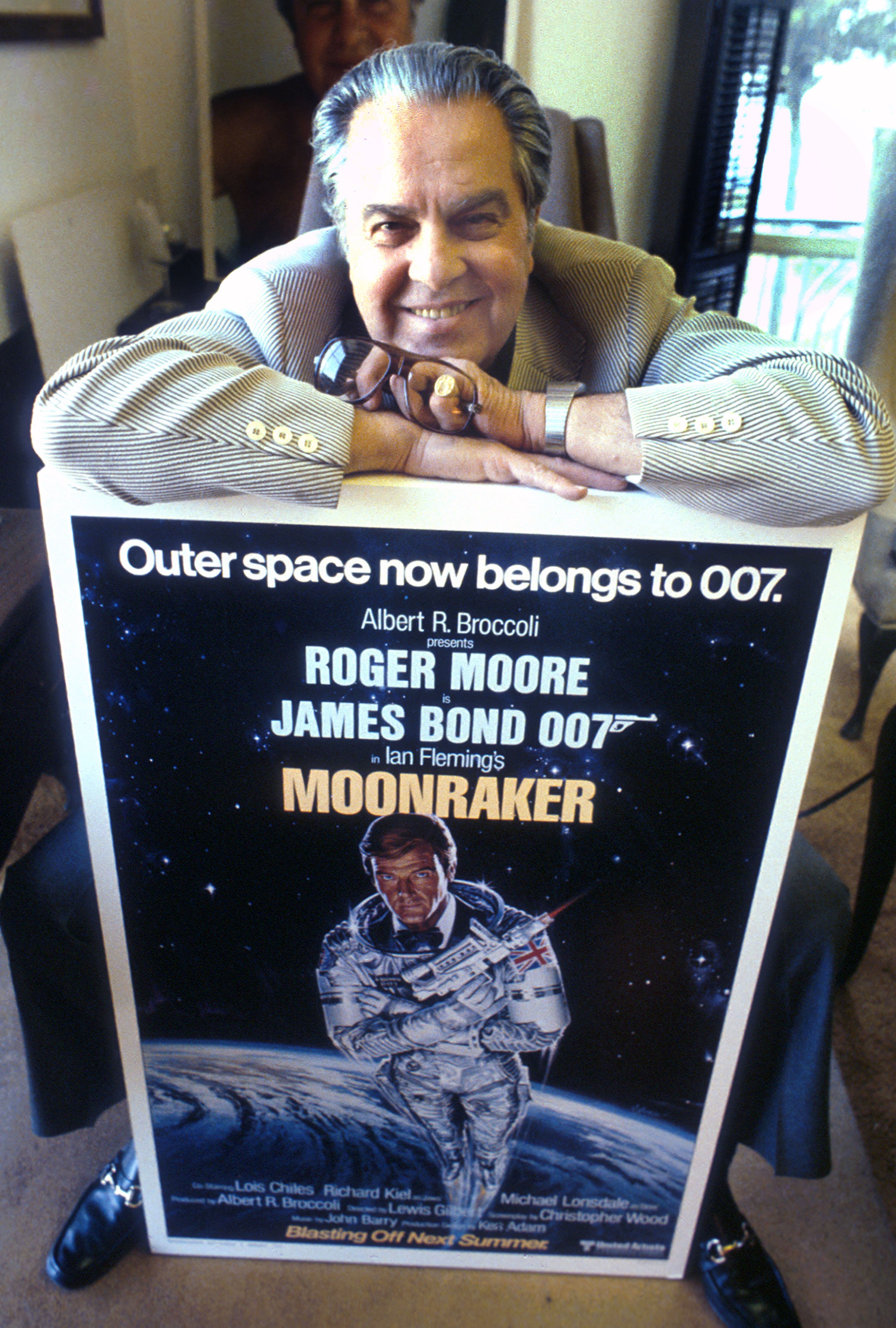 O produtor Albert Broccoli posa com o cartaz de ' Moonraker’ (007 – Contra o foguete da Morte), na Califórnia, em 1979. / TOM NEBBIA / GETTY IMAGES