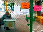 A guard remains at the entrance of a public school with signs reading "There Will Be No Class" after the Brazilian government decided to close schools for five days to prevent the advance of the new coronavirus, COVID-19, in Brasilia, on March 12, 2020. (Photo by Sergio LIMA / AFP)