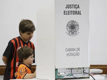 Crianças olham para urna eletrônica durante sessão em colégio eleitoral de São Paulo.