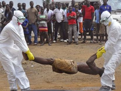 Trabalhadores da saúde retiram cadáver de homem suspeito de morrer de ebola.