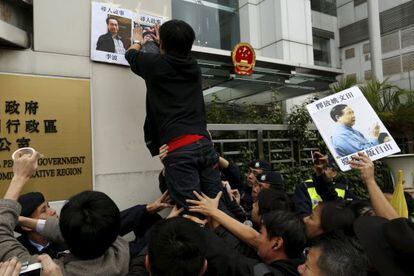 Um ativista coloca um cartaz em frente ao escritório de representação chinesa em Hong Kong com as fotos de Lee Bo e Lu Bo, que estão desaparecidos.