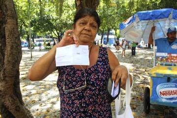 Wancy Conceição Amaral, de 64 anos, mostra sua carteira com boletos a serem pagos como único conteúdo.