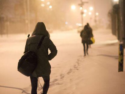 Pedestres caminham por uma rua nevada em Nova York.