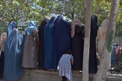 Mulheres afegãs que fugiram do avanço dos talibãs esperam para receber comida de ajuda humanitária em um parque de Cabul, na sexta-feira.
