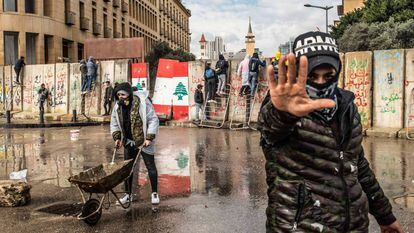 Vários manifestantes tentam atravessar as barreiras de concreto erguidas em 11 de fevereiro para impedir que civis entrem no Parlamento libanês, em Beirute.