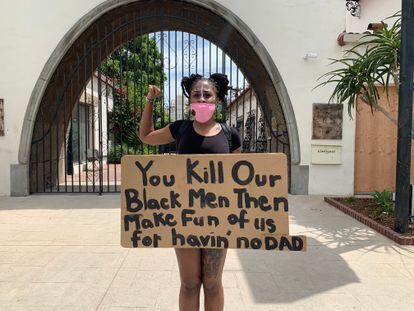 Natasha Jennings segura um cartaz com a legenda: “Matam homens negros e depois zombam de nós por não ter pais”.