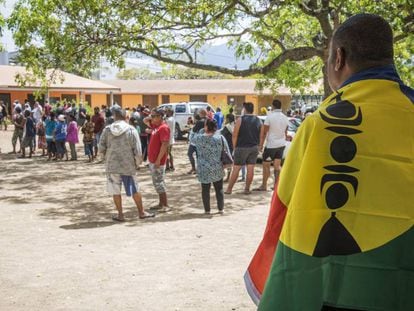 Homem com a bandeira da Nova Caledônia aguarda para votar.