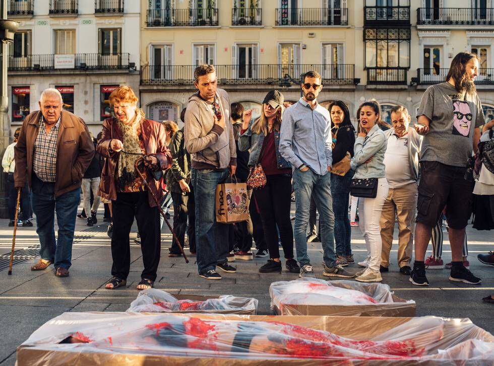 Ativistas da Puerta del Sol, em Madri, realizam uma ação de “empacotamento”, na qual fingem estar ensanguentados e embalados em plástico.