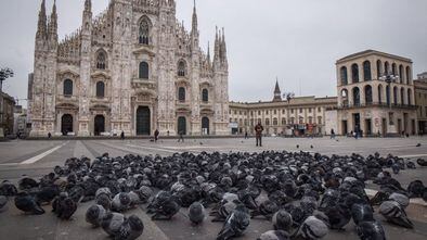 Pombos e poucas pessoas na praça do Duomo, a principal de Milão, deserta devido ao coronavírus.