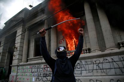 Um homem protesta em frente ao Congresso da Guatemala, que foi incendiado por alguns manifestantes.
