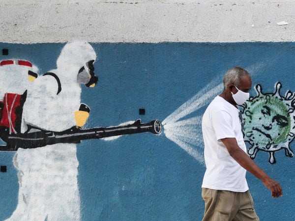 FILE PHOTO: A man walks next to a graffiti depciting a cleaner wearing protective gear spraying viruses with the face of Brazil's President Jair Bolsonaro amid the coronavirus disease (COVID-19) outbreak, in Rio de Janeiro, Brazil, June 12, 2020. REUTERS/Sergio Moraes/File Photo