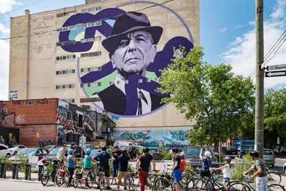 Ciclistas diante de um mural de Leonard Cohen em um edifício de Montreal, cidade natal do cantor canadense.